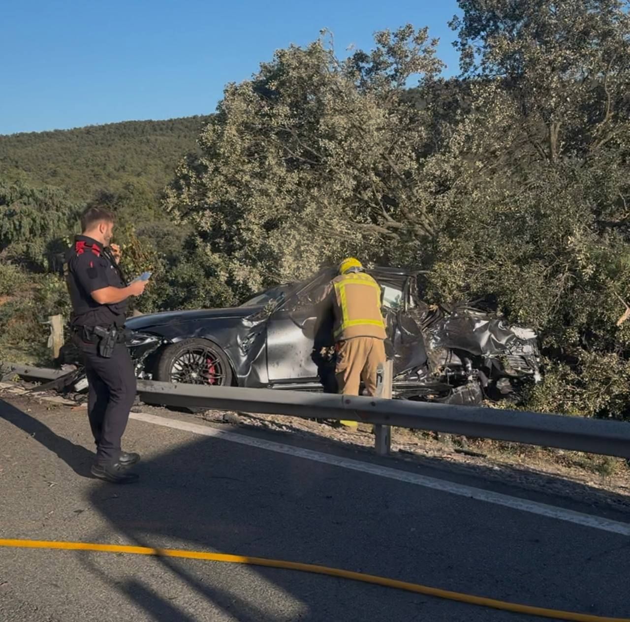 Un bomber revisa el vehicle davant d'un mosso d'esquadra.